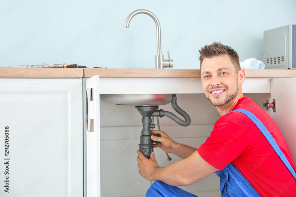 Plumber installing sink in kitchen