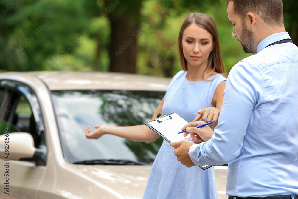 Young woman and insurance agent near damaged car outdoors