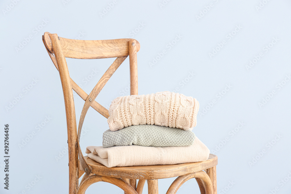 Chair with winter clothes on color background