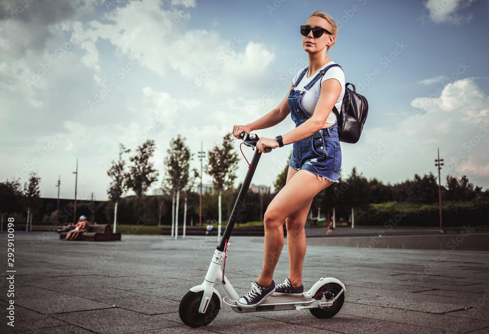 年轻漂亮的女人骑着电动滑板车，现代一代