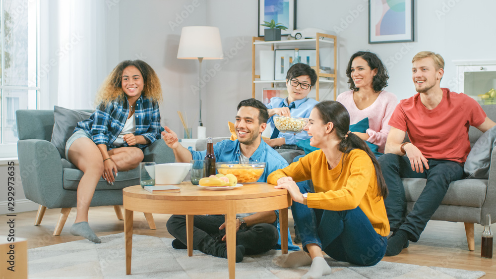 At Home Diverse Group Friends Watching TV Together, Eating Snacks and Drinking Beverage. They Probab