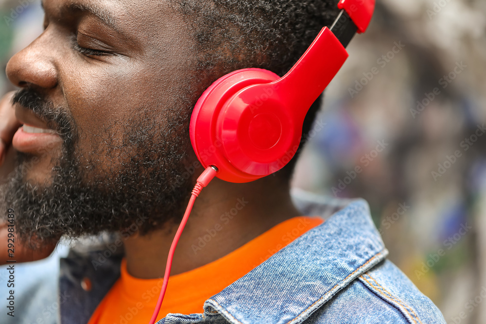 Handsome African-American man listening to music outdoors, closeup