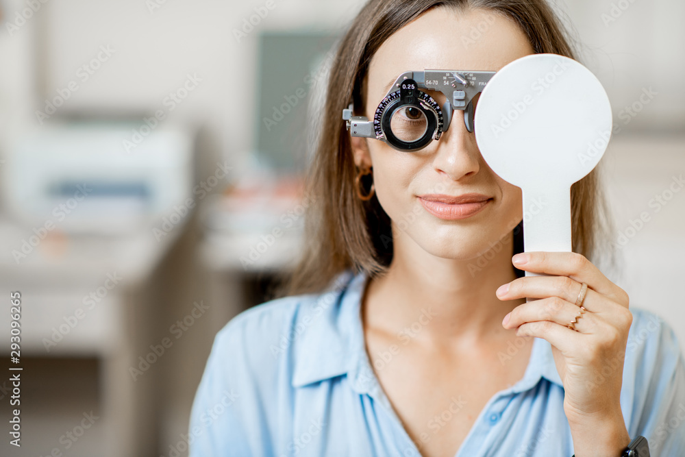 Young woman checking vision with eye test glasses during a medical examination at the ophthalmologic