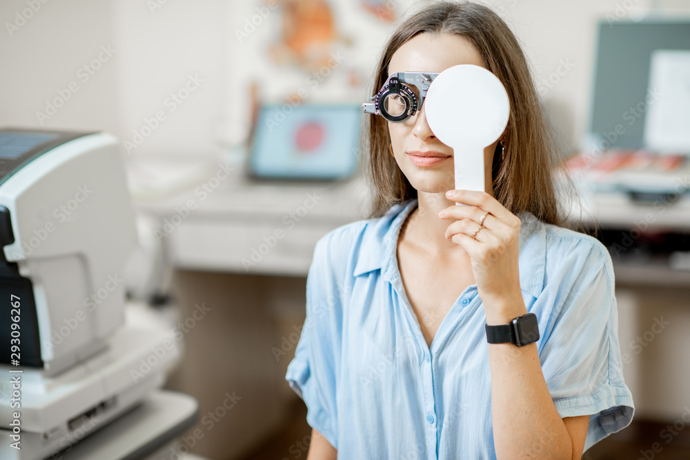 Young woman checking vision with eye test glasses during a medical examination at the ophthalmologic