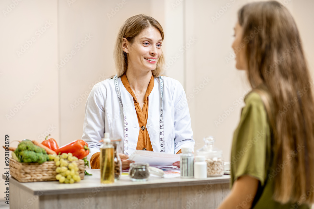 Nutritionist with young woman client talking about meal plan and healthy products during a medical c