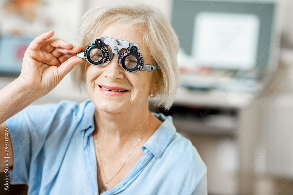 Senior woman checking vision with eye test glasses during a medical examination at the ophthalmologi