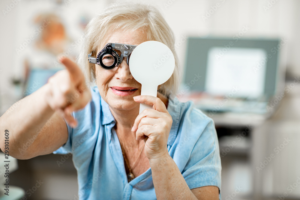 Senior woman with poor eyesight checking vision squinting her face during a medical examination at t