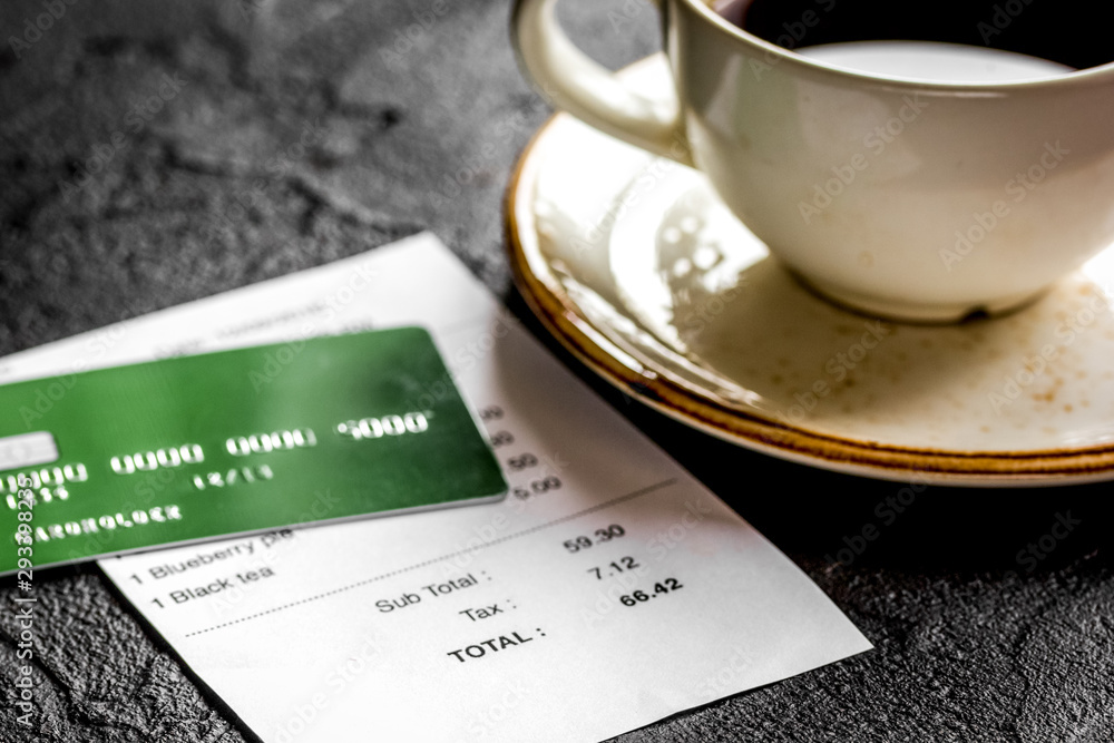 coffee and receipt bill for payment by credit card on dark table background