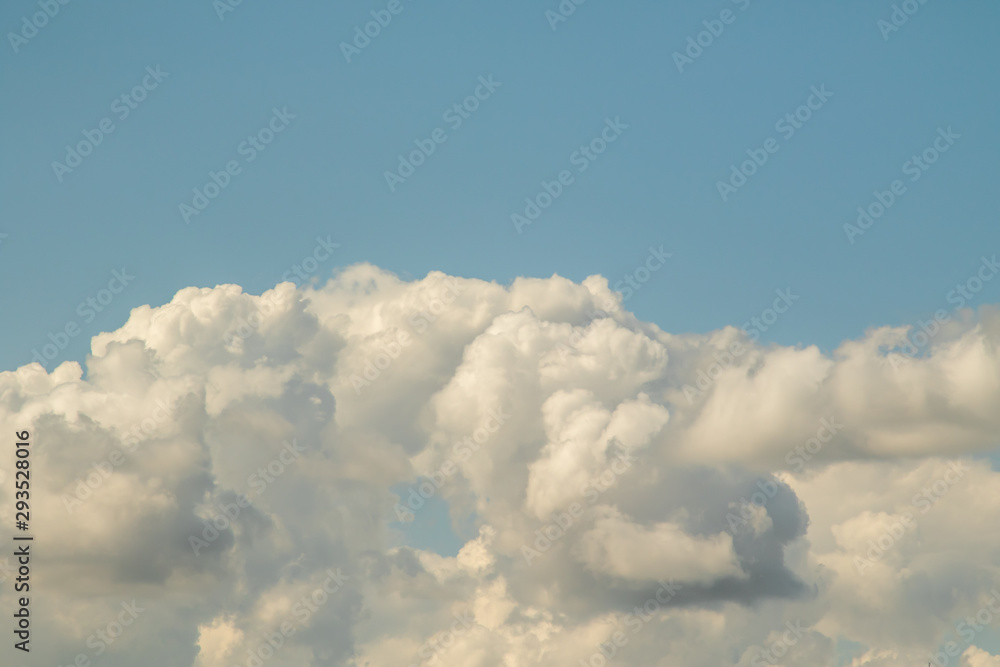 White powerfully cumulus clouds on a blue sky.