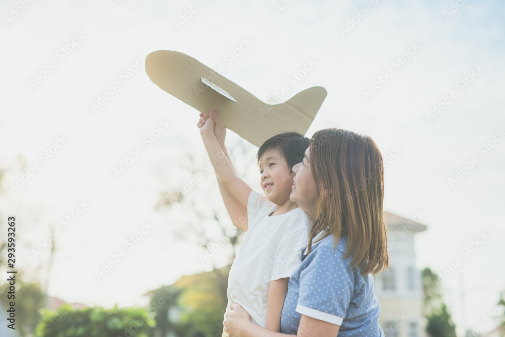 Asian mother and son playing cardboard airplane together