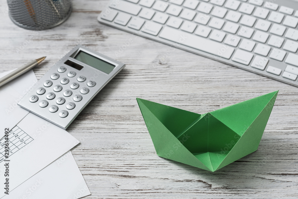 Top view office workspace with green paper ship