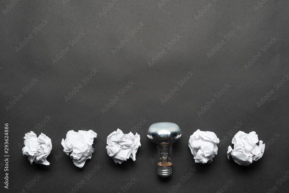 Lightbulb and crumpled white paper balls