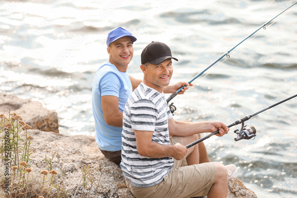 Young man and his father fishing on river