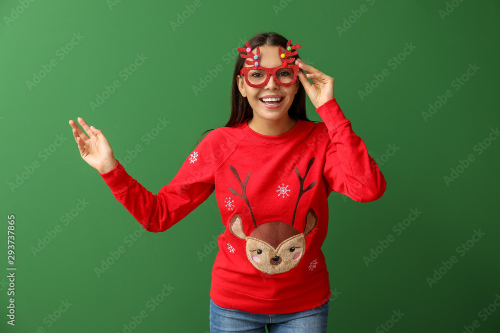 Young woman in Christmas sweater on color background