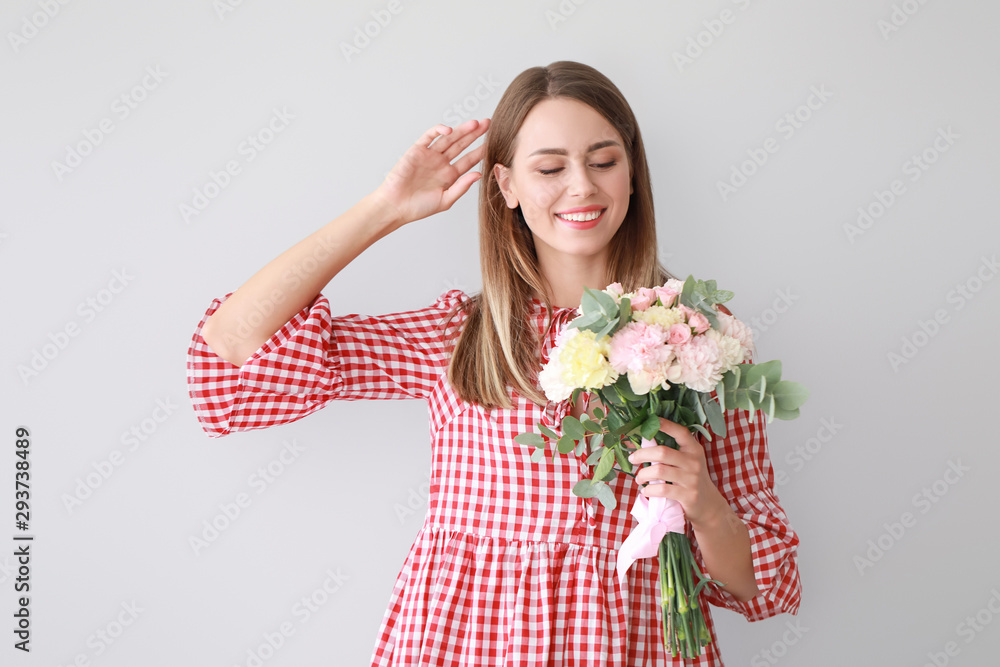 Beautiful young woman with bouquet of carnation flowers on light background