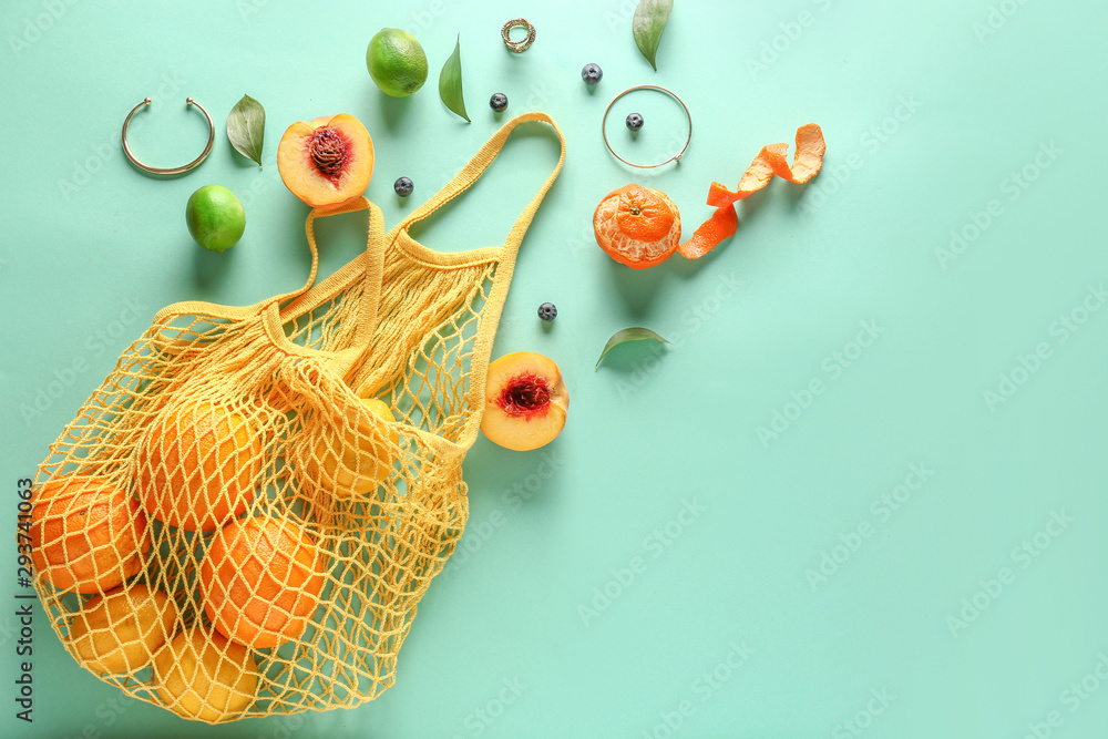 Mesh bag with fresh fruits on color background