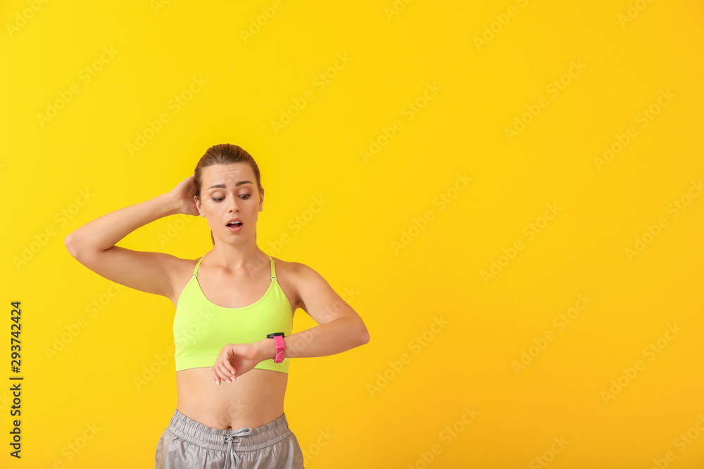 Worried young woman with watch on color background