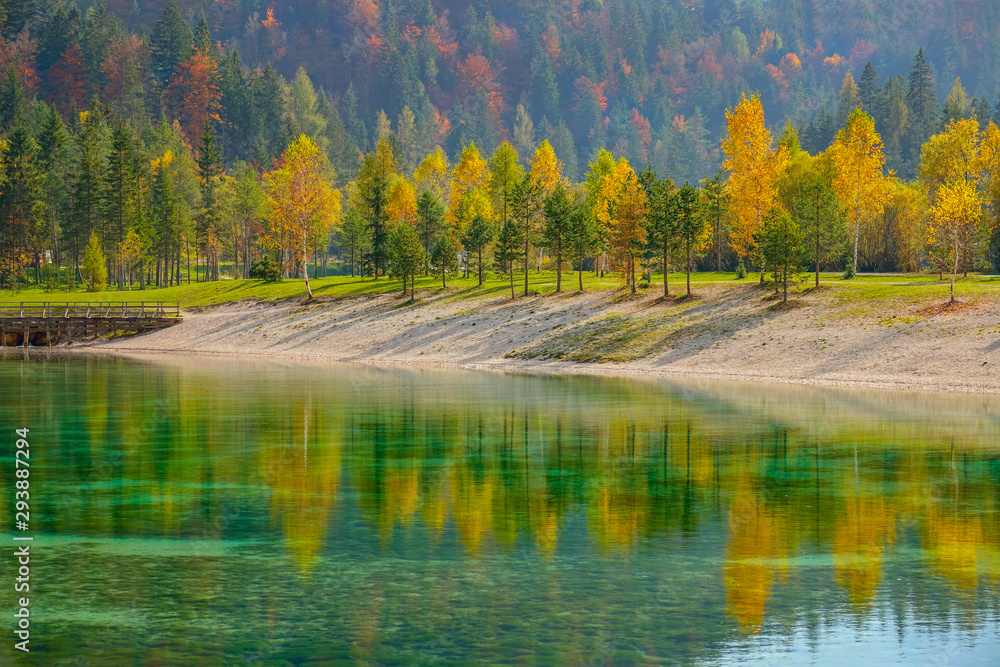 Colorful fall colored trees are reflected in the breathtaking emerald lake.