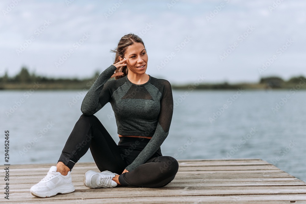 Beautiful fit woman relaxing on a river dock.