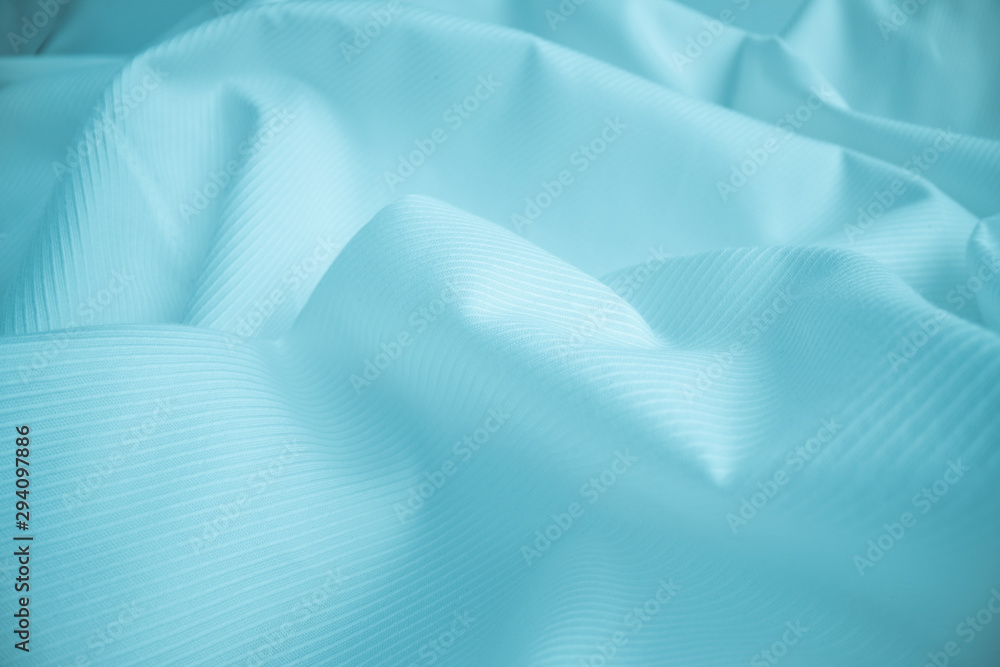 Shiny flowing cloth texture in macro shot. Wavy clean silk weave material. Textile abstract backgrou