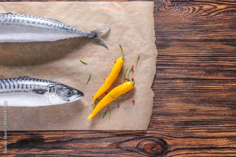 Parchment with raw mackerel fish on wooden table