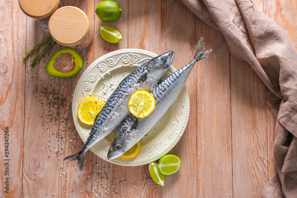 Plate with raw mackerel fish on wooden table