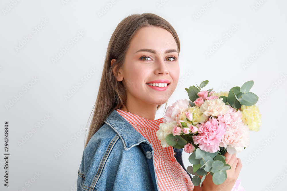 美丽的年轻女子，浅色背景上有一束康乃馨花