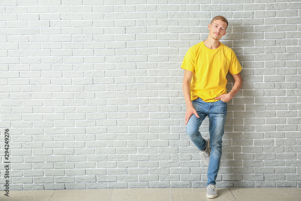 Young man in stylish t-shirt near brick wall