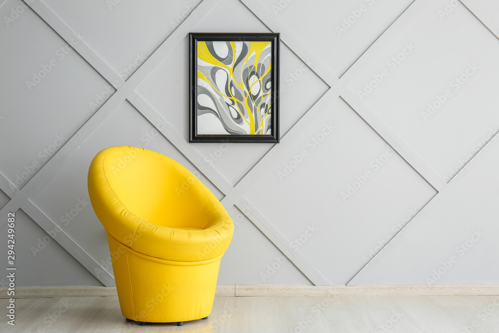 Stylish armchair with picture on grey wall in room