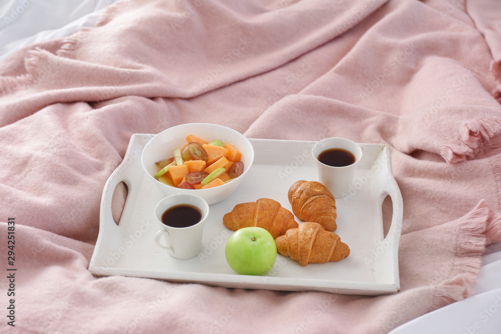 Tray with tasty breakfast on bed