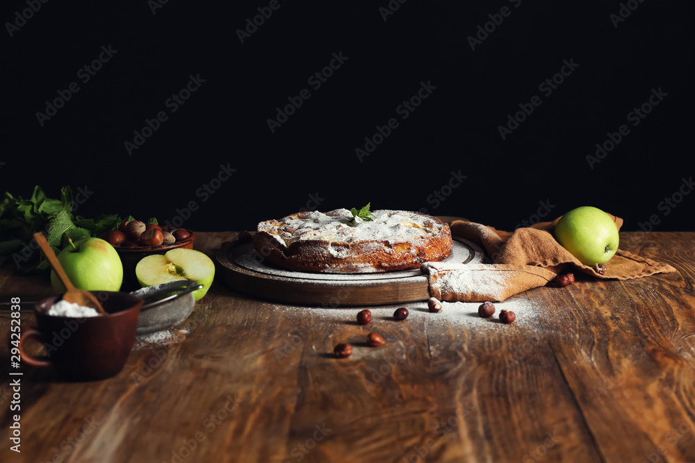 Tasty apple pie with sugar powder on wooden table