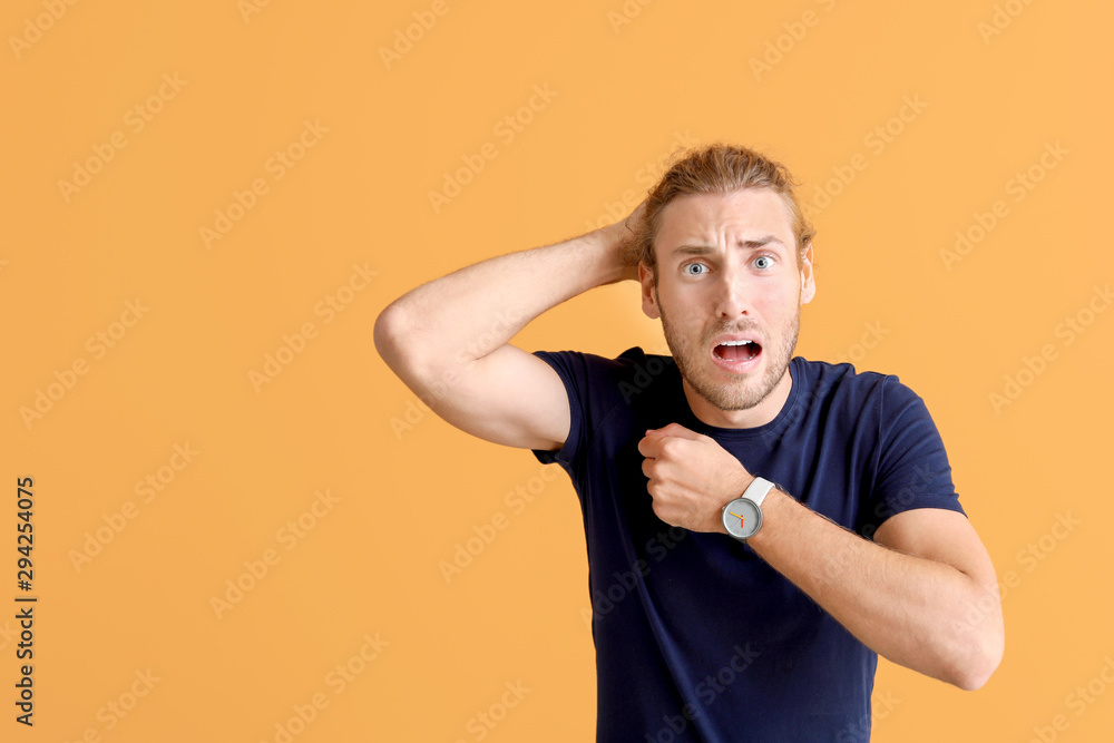 Stressed man with watch on color background