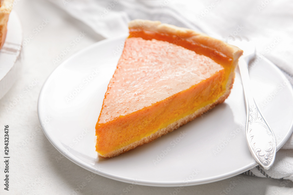 Plate with piece of tasty pumpkin pie on table