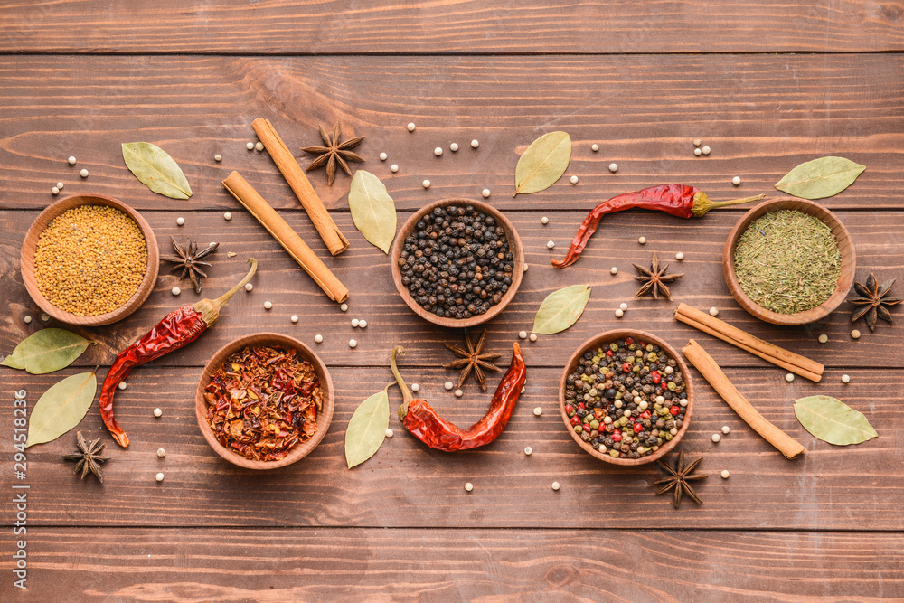 Bowls with different spices on wooden background