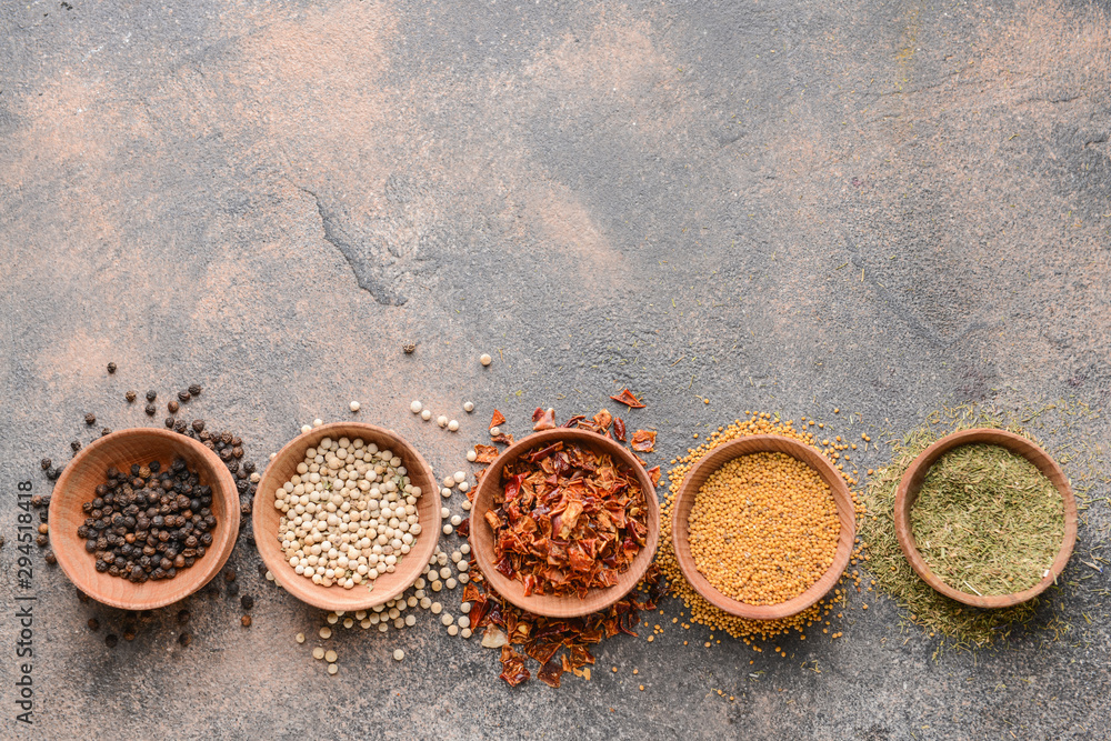 Bowls with different spices on grey background