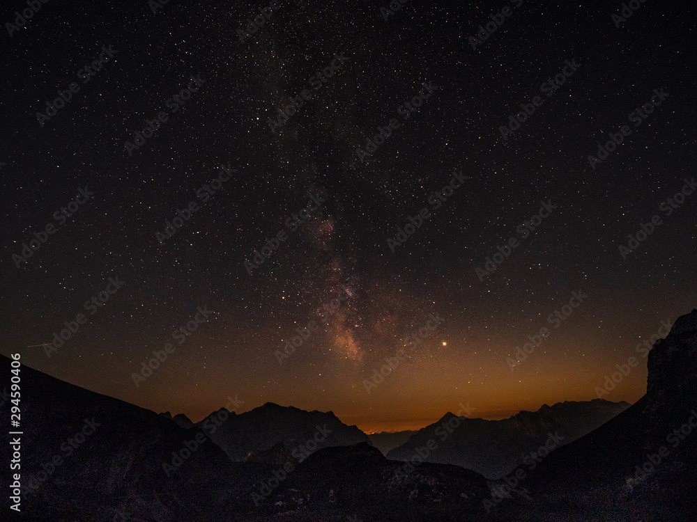 Golden evening light gently illuminates the mountains under the starry sky.