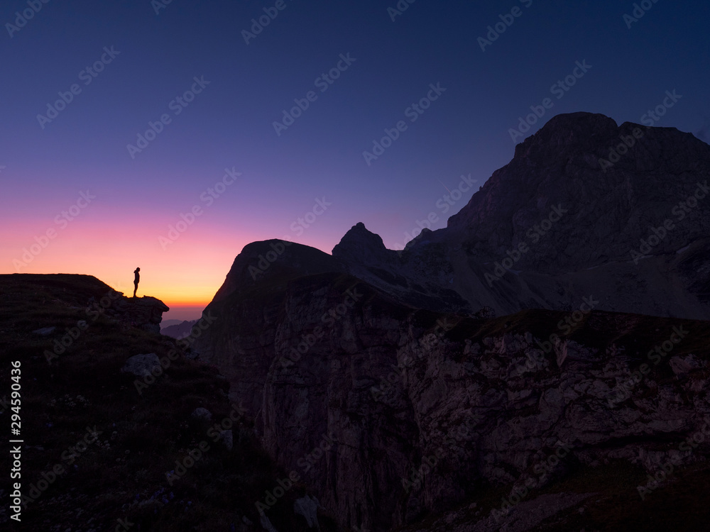 沉默：一个不知名的徒步旅行者在金色日出时面对着岩石山。