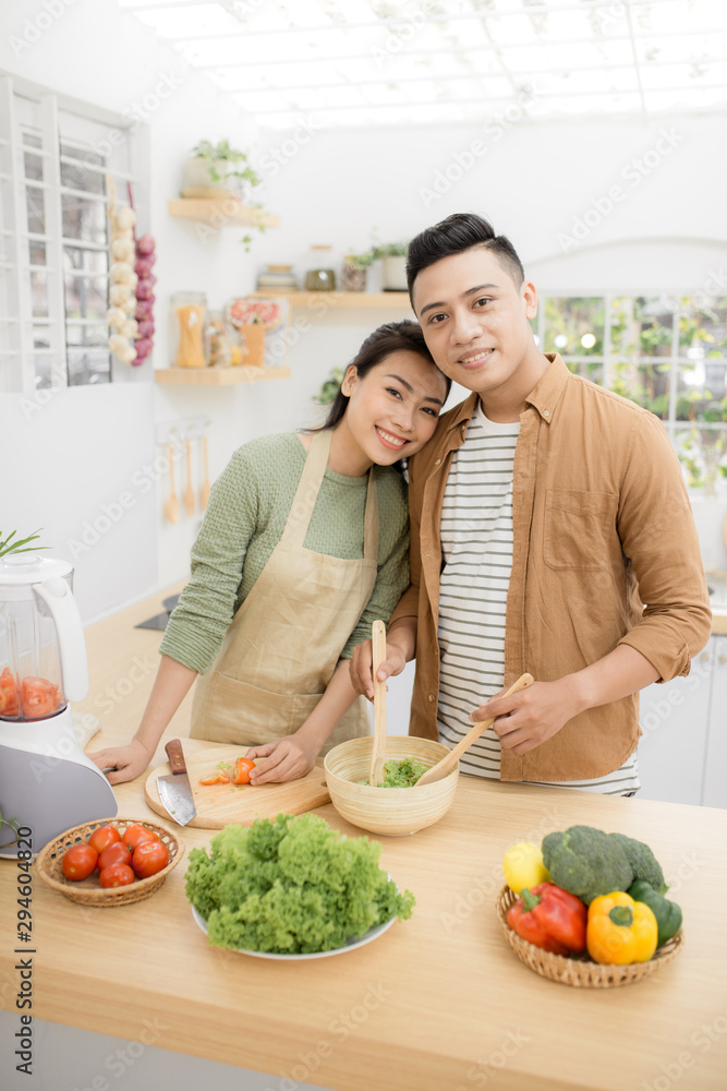 微笑的亚洲年轻夫妇在厨房做饭