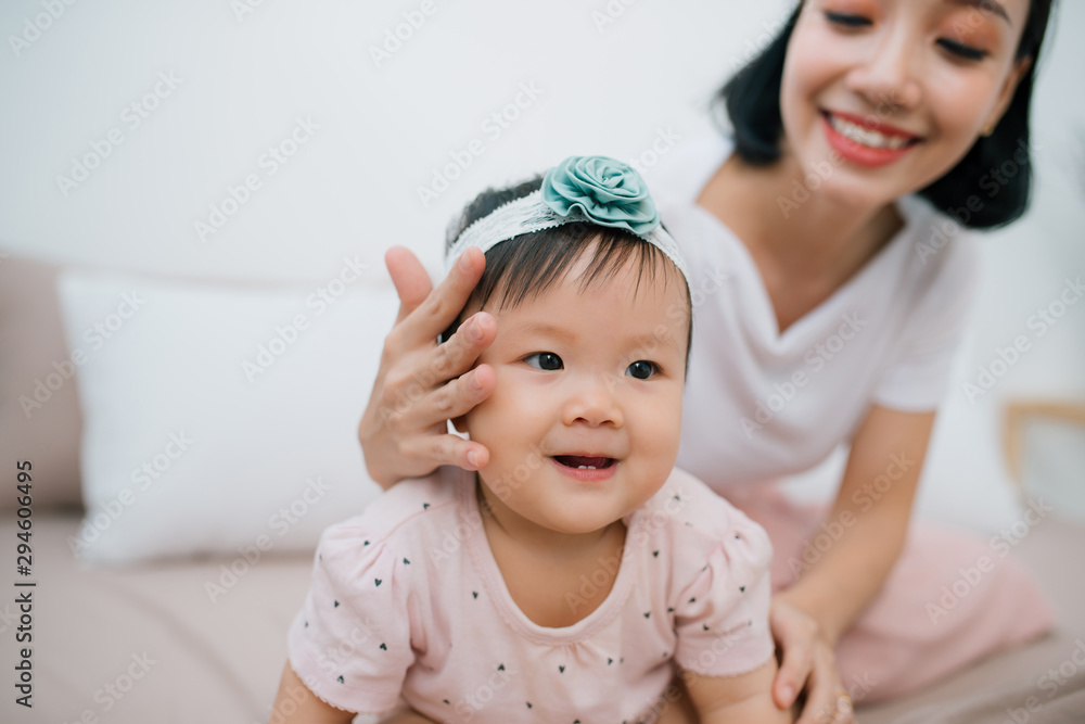 小女孩坐在家里的床上。一位年轻的母亲紧紧抓住一个有头发的女儿