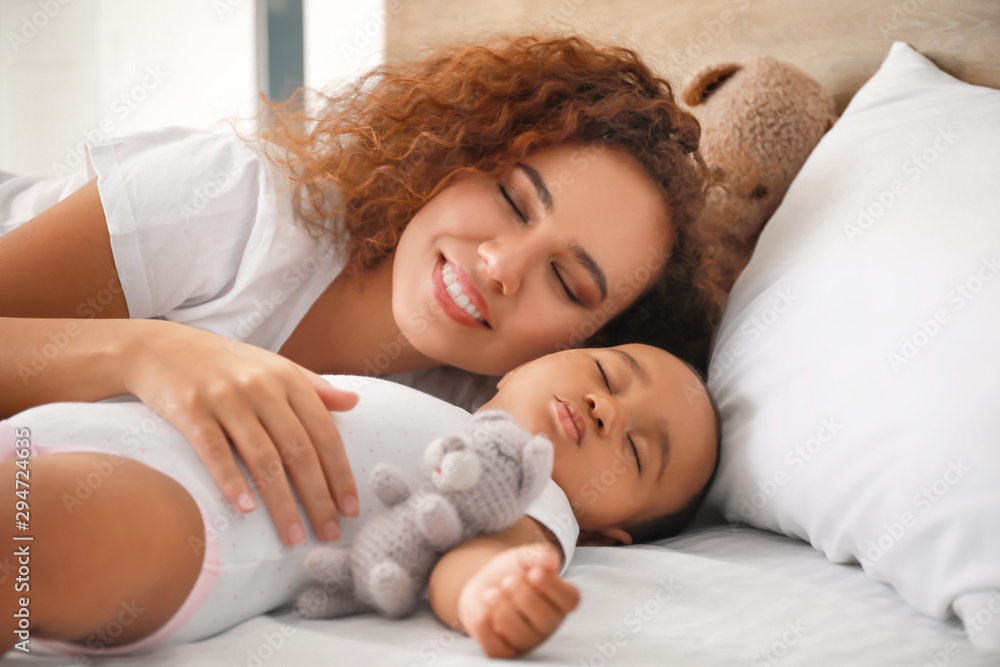 Young African-American woman and her baby sleeping on bed