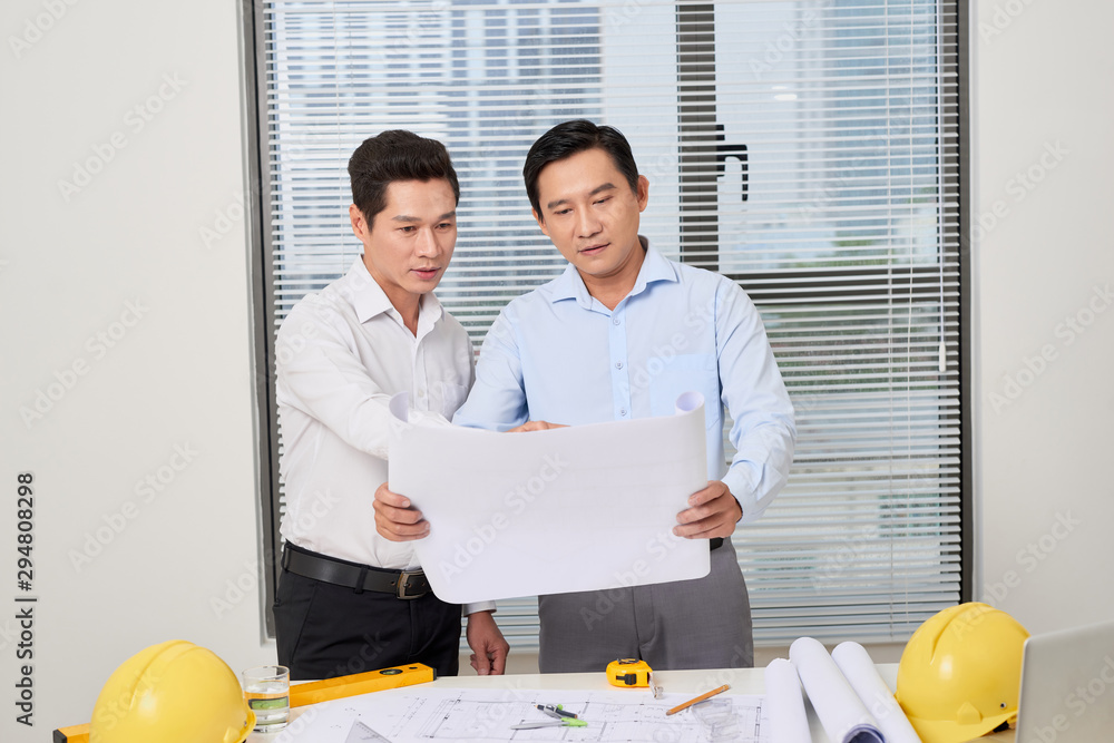 Two architects standing at a desk and discussing a project