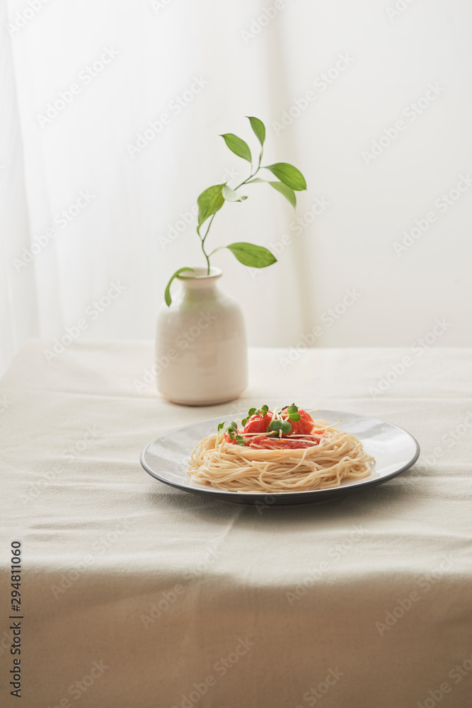 食物，白盘子里的意大利肉酱意大利面和白桌子上的一瓶植物