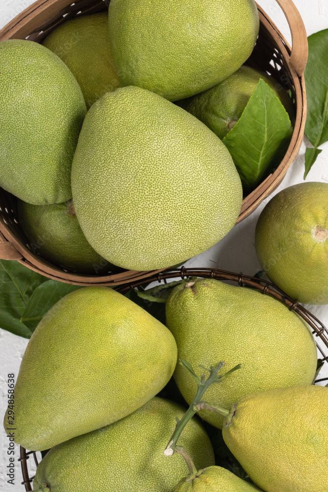 Fresh pomelo, pummelo, grapefruit, shaddock on white cement background in bamboo basket. Autumn seas