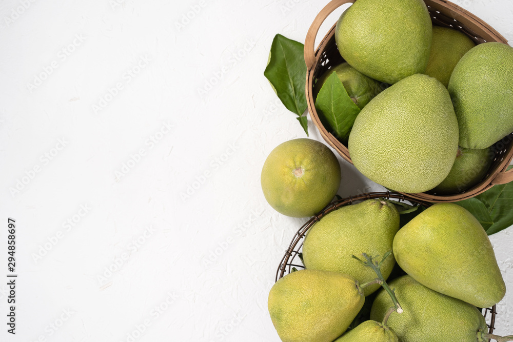 Fresh pomelo, pummelo, grapefruit, shaddock on white cement background in bamboo basket. Autumn seas