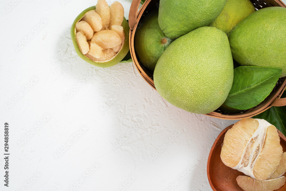 Fresh pomelo, pummelo, grapefruit, shaddock on white cement background in bamboo basket. Autumn seas