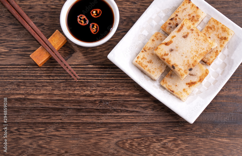 Delicious turnip cake, Chinese traditional local radish cake in restaurant with soy sauce and chopst