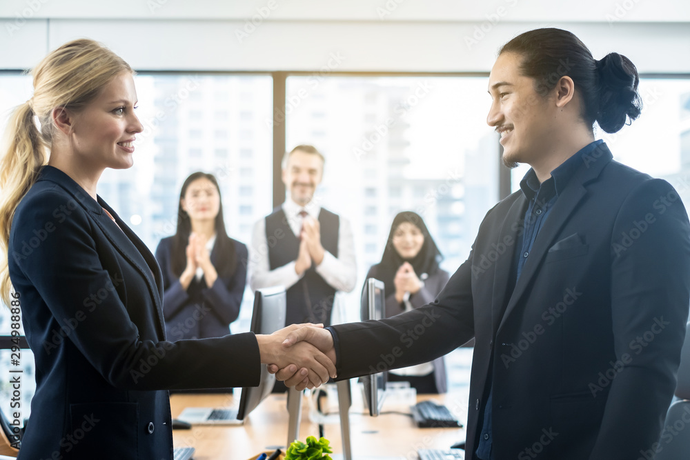 Handshake of successful agreement or negotiation between business Caucasian woman and Asian man in w