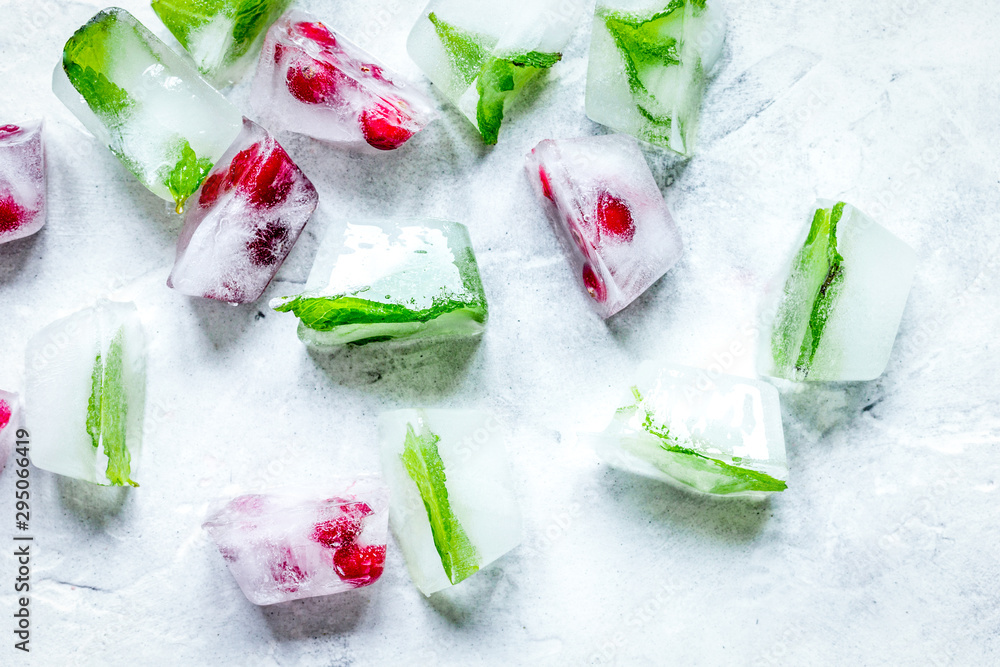 mint and red berries in ice cubes stone background top view