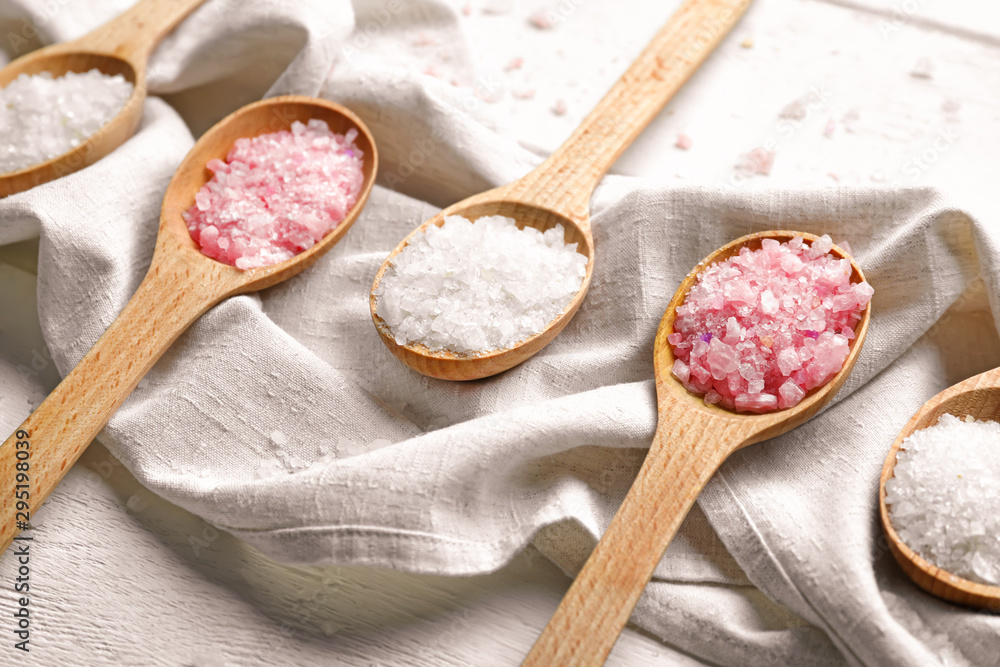 Spoons with sea salt for spa procedures on table