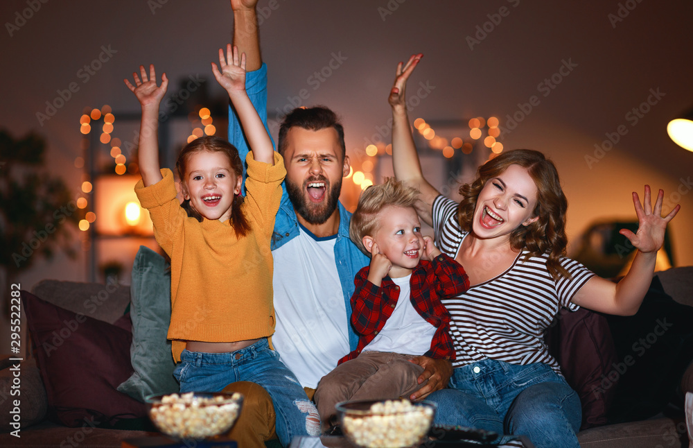 family mother father and children watching projector, TV, movies with popcorn in   evening   at home